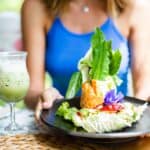 woman in cute blue top having spicy fresh salad with salmon and vegetables